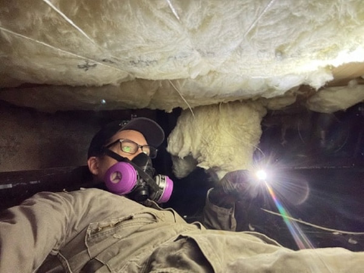 Technician sealing a foundation vent in an older Plano, TX home's crawl space